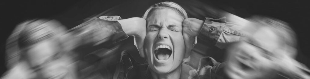 Vrouw met handen op haar hoofd, overweldigd door huidige patronen. Een direct gevolg van onverwerkte kindertijd-imprints die diep in haar systeem liggen. 